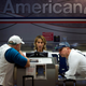 Two unidentified American Airlines passengers talk to a customer service representative, center in Miami.